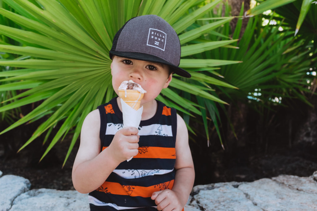 toddler eating an ice cream cone wearing a billabong hat
