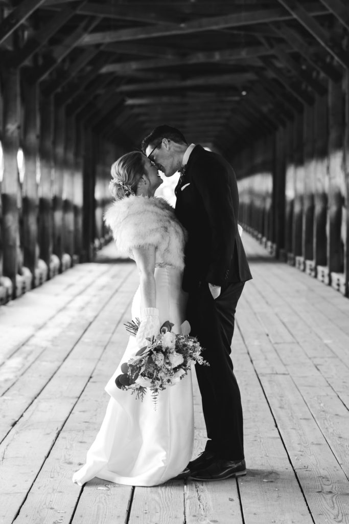 bride and groom kissing on Wakefield covered bridge in black and white