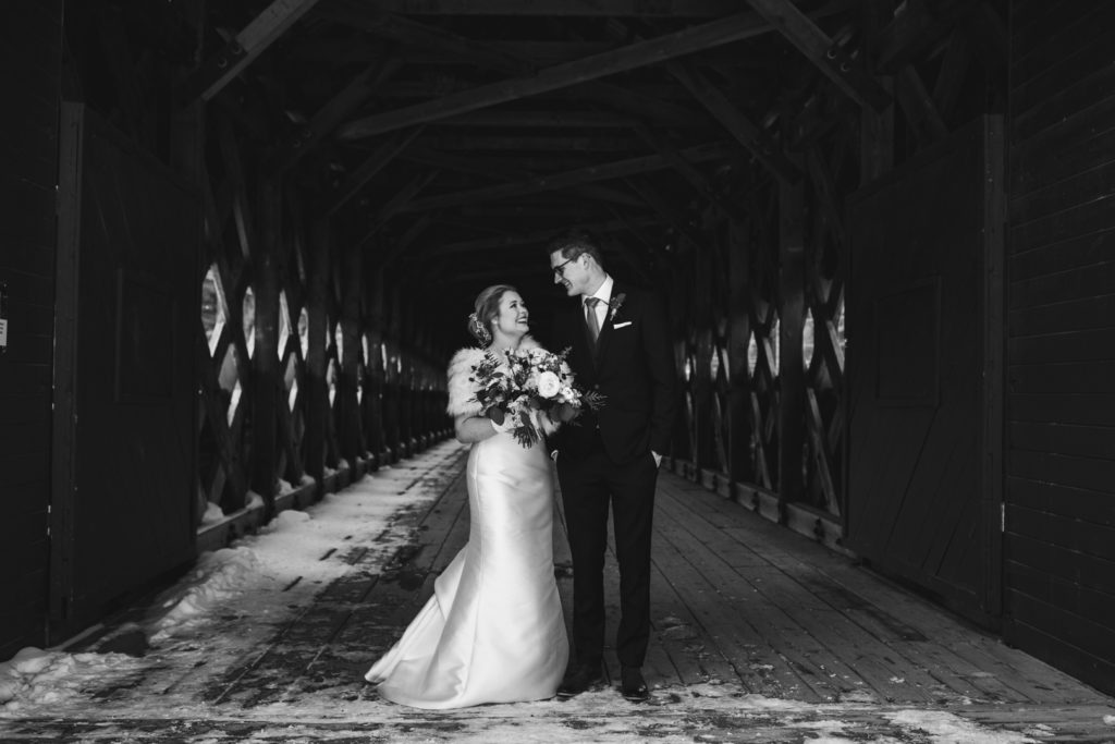 Bride and groom smiling on Wakefield covered bridge in black and white