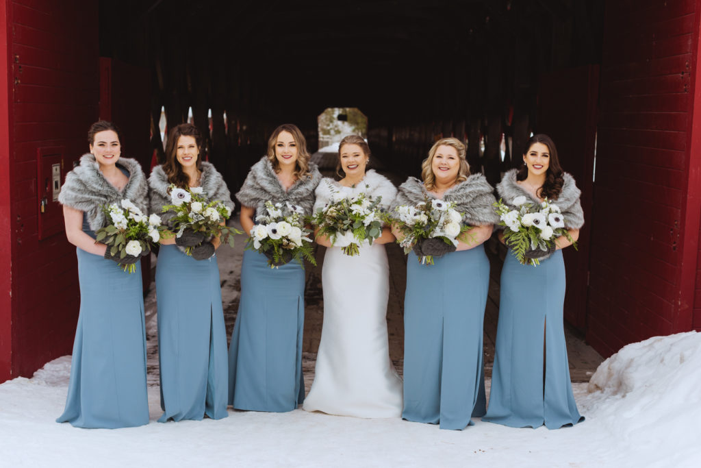 bridesmaids in long blue dresses wearing furs