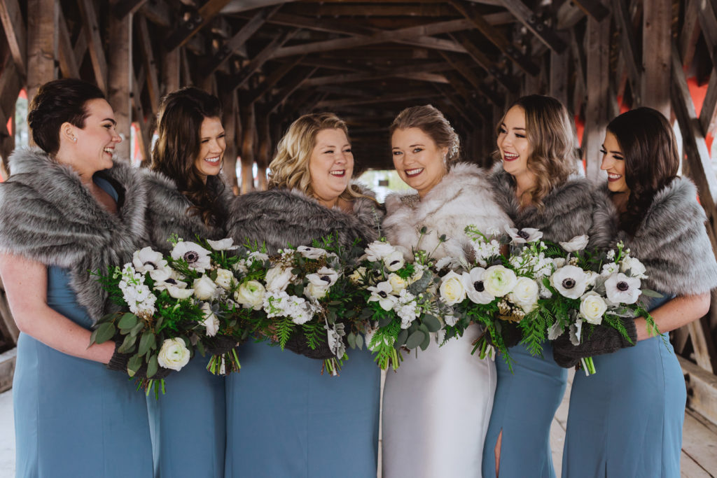 bridesmaids in long blue dresses wearing furs