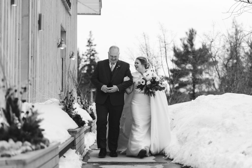 bride and her father walking towards the aisle smiling