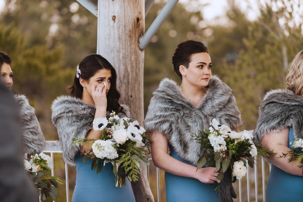bridesmaid wiping away a tear during wedding ceremony