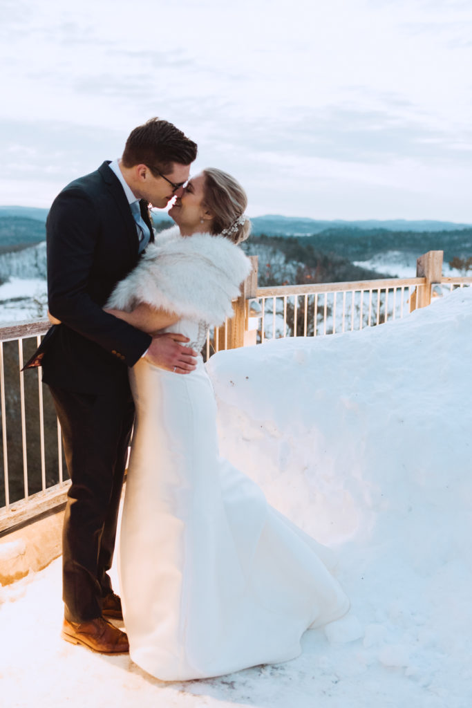 bride and groom kissing in the snow at sunset
