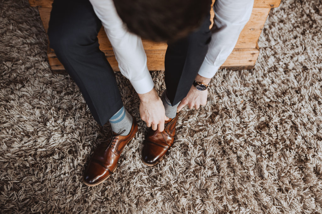 overhead photo of groom putting on his shoes