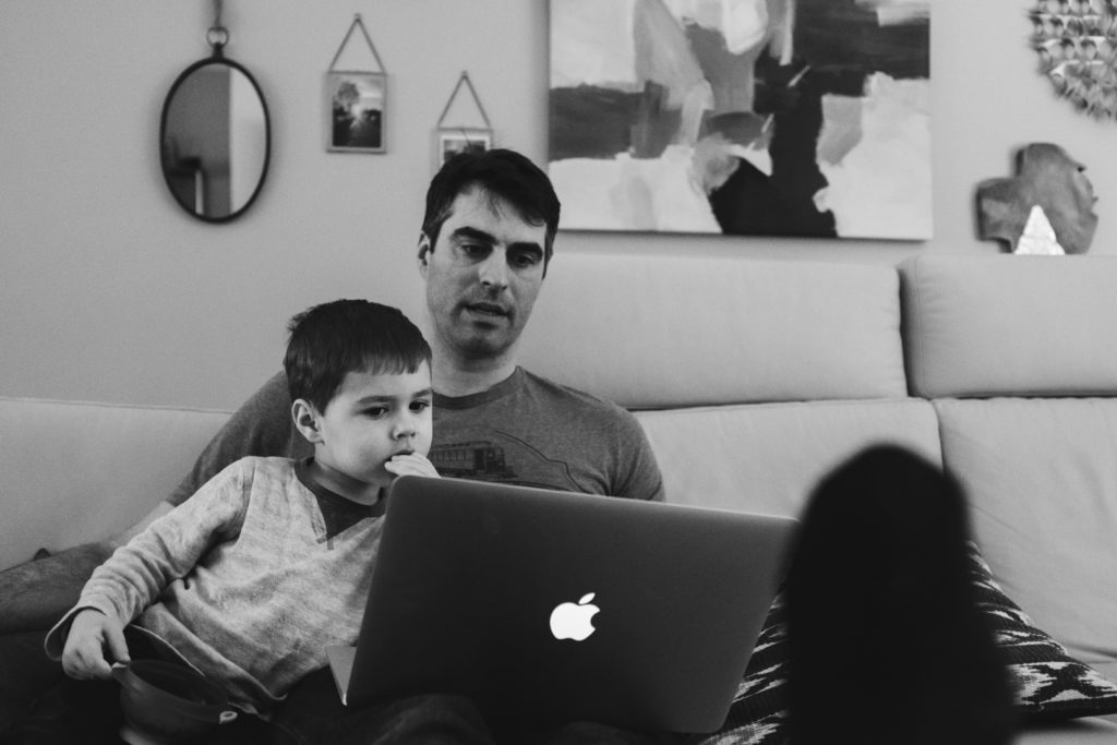 toddler looking at photos on laptop with dad