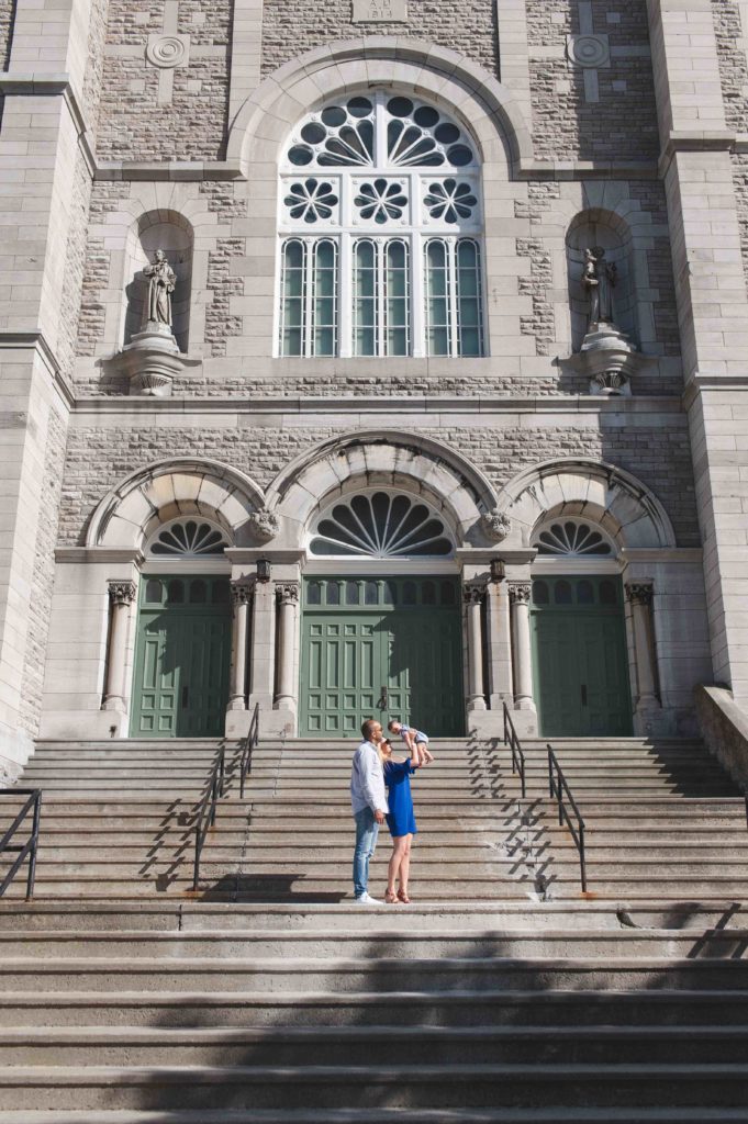 Parents holding up their baby in front of old church in Ottawa