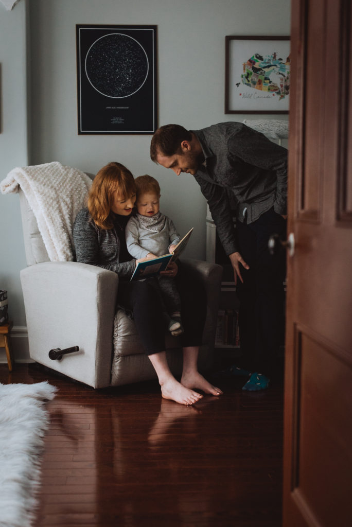 mother and father reading a book to their son in his room