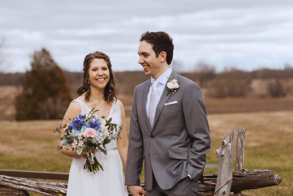 bride and groom laughing in a field at spring wedding