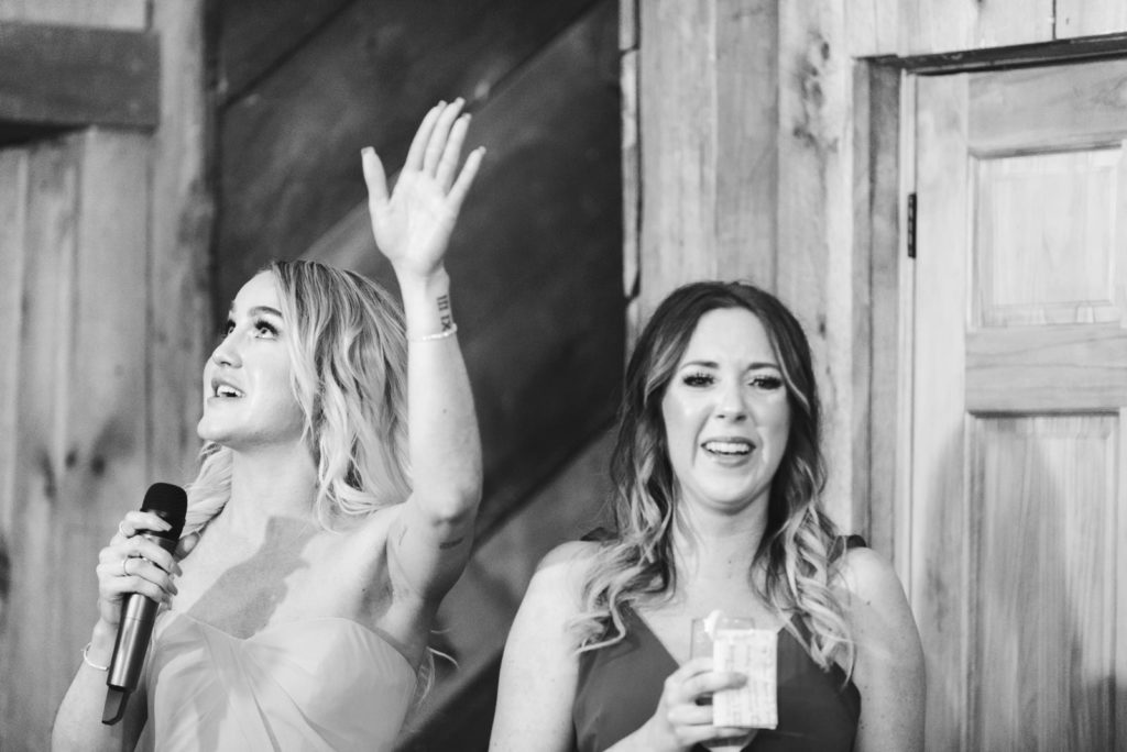 bridesmaids laughing while giving a speech at wedding reception