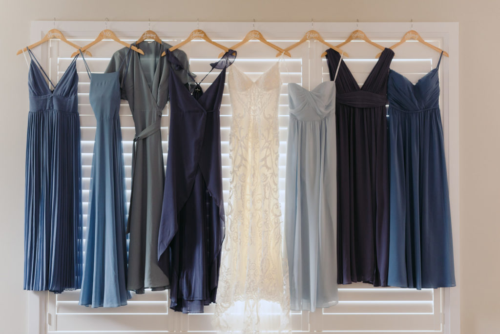 bride and bridesmaid's dresses hanging by the window