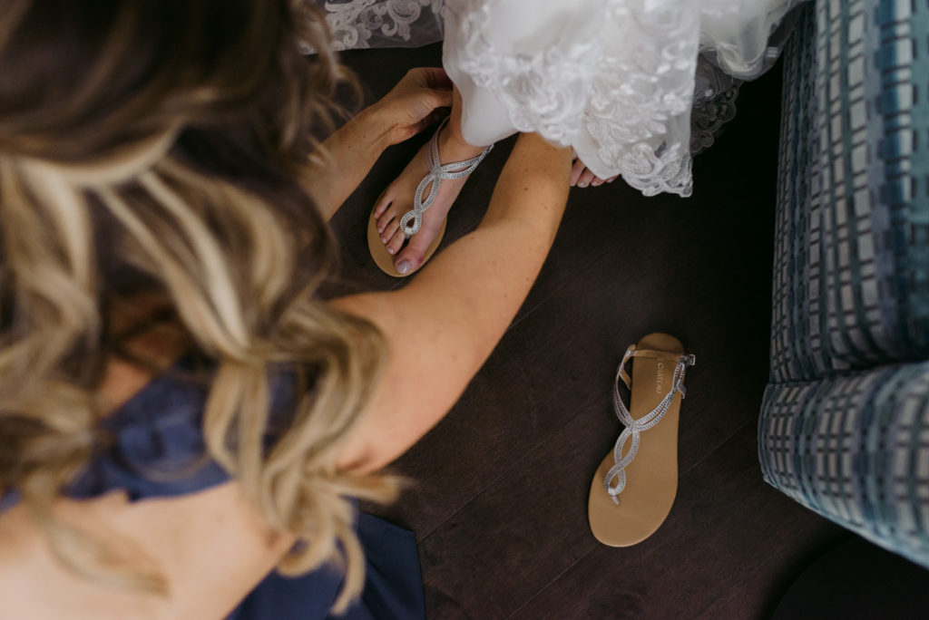 bridesmaid helping the bride tie up her shoes