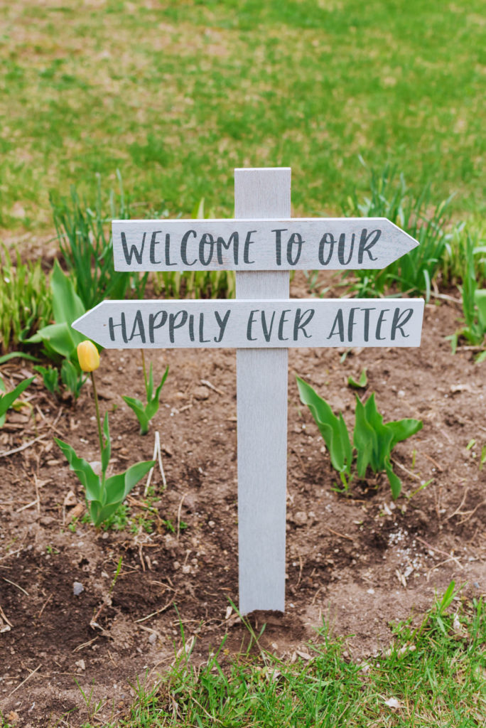 welcome to our happily ever after sign in the garden outside of the church