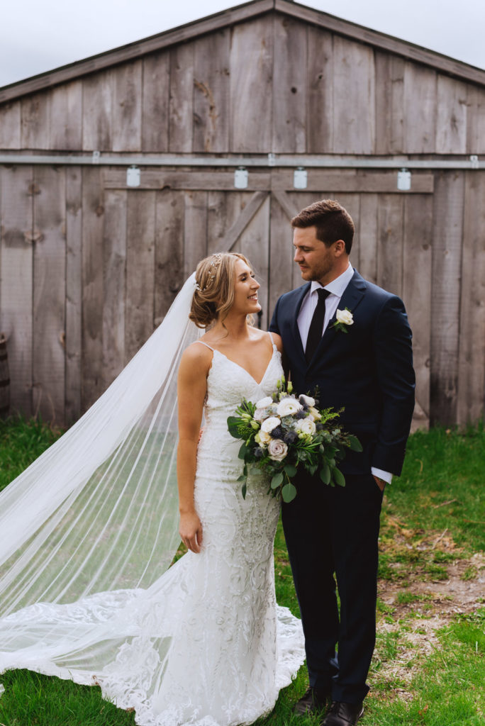 bride and groom in front of wooden barn