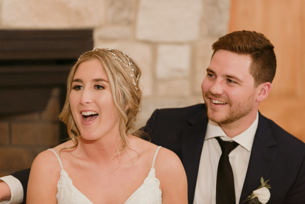 bride and groom laughing at speeches at wedding reception