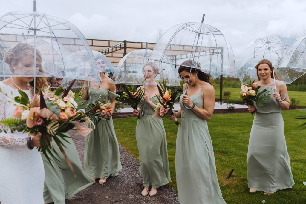 bride and bridesmaids holding clear umbrellas on rainy wedding day
