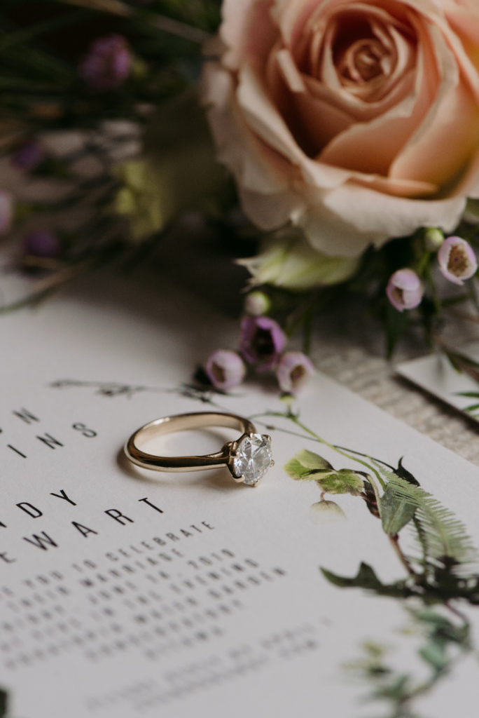 engagement ring with wedding invitation and florals