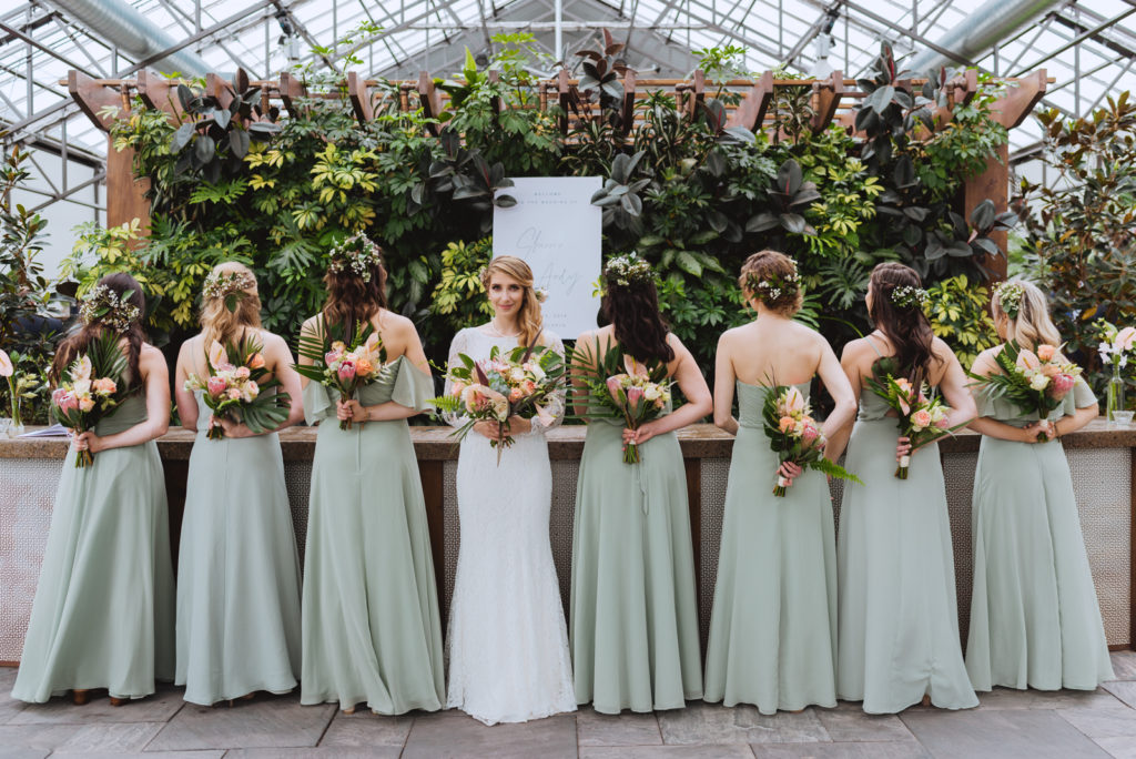 sage green bridesmaids dresses with boho bouquets in greenhouse
