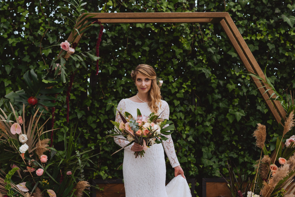 bride under wooden arch at greenhouse wedding