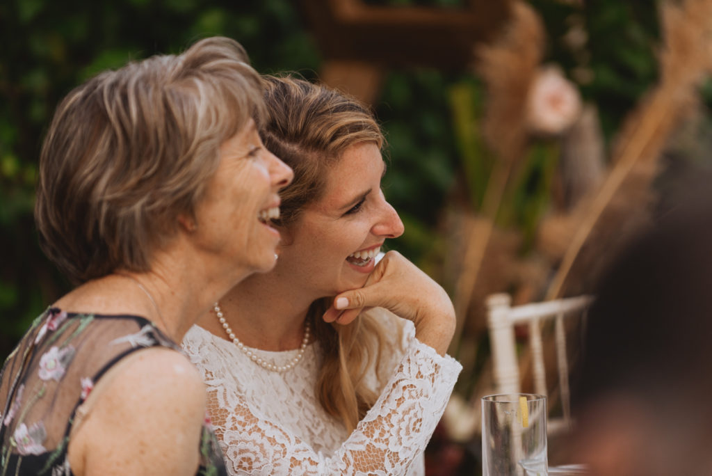 bride and her mother laughing during wedding reception speeches