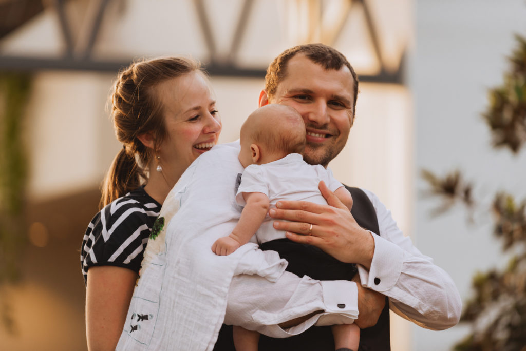 couple with baby during wedding reception at sunset