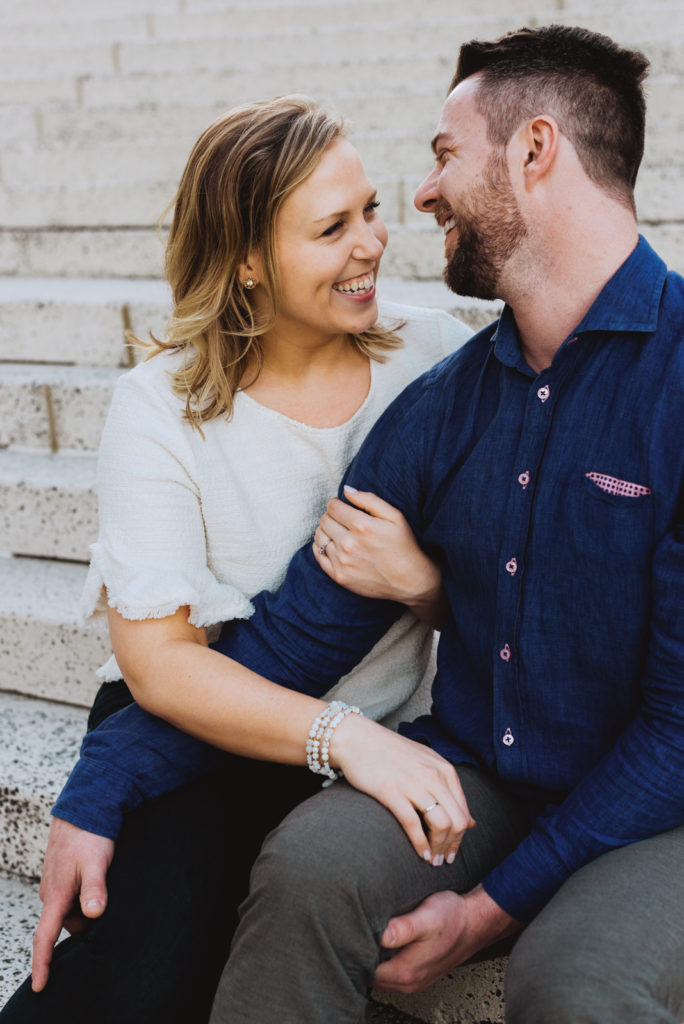 Engaged couple laughing sitting on stone staircase