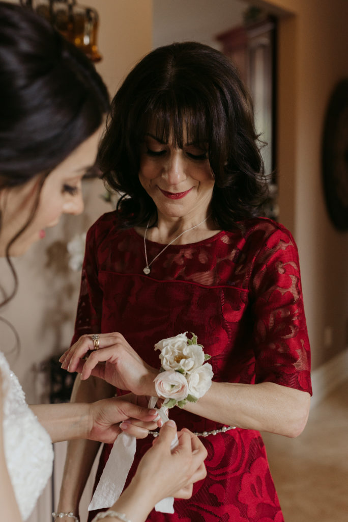 bride putting on her mother's corsage