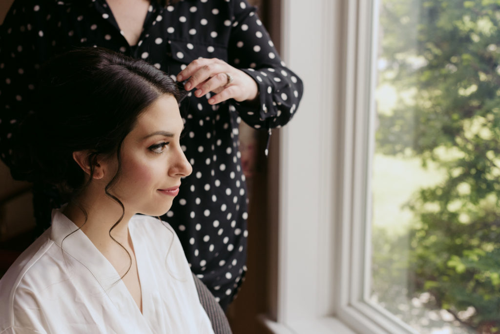 bride looking out the window while she gets her hair done