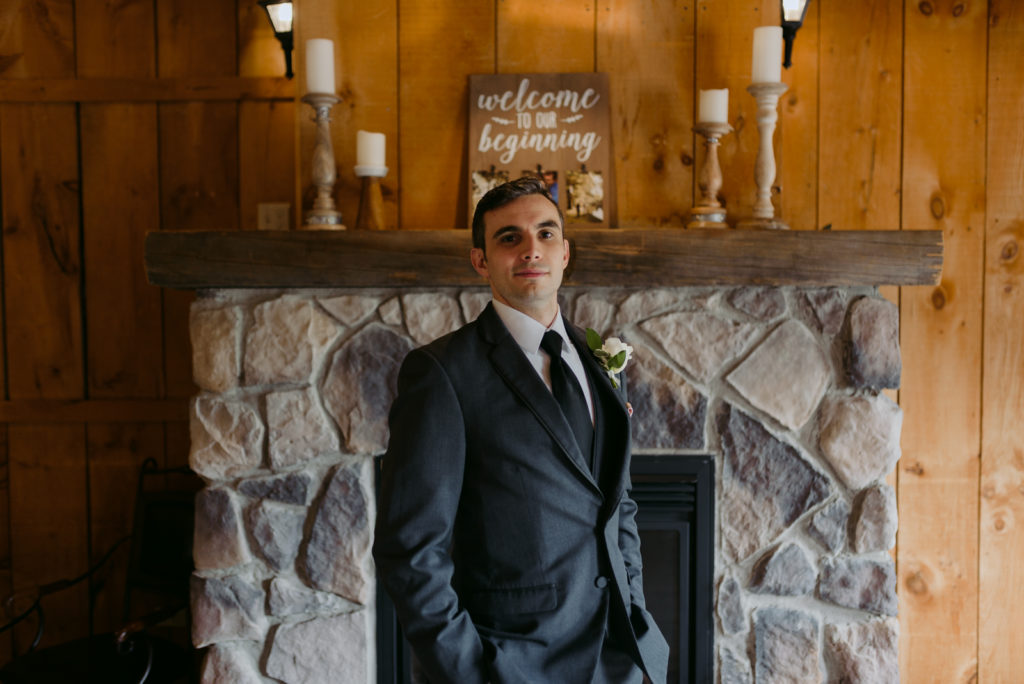 groom in front of fireplace at the Strathmere Lodge