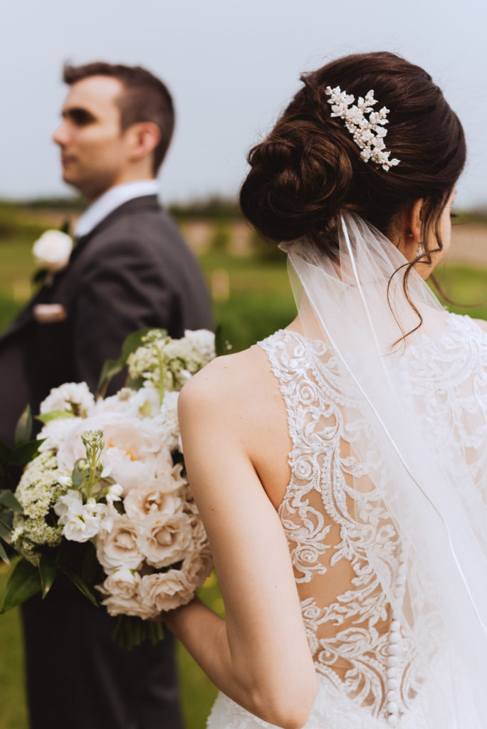 back of bride's dress holding bouquet of white flowers