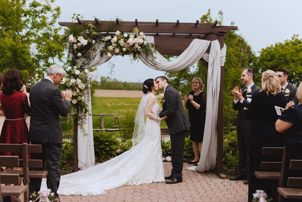 bride and groom first kiss under pergola