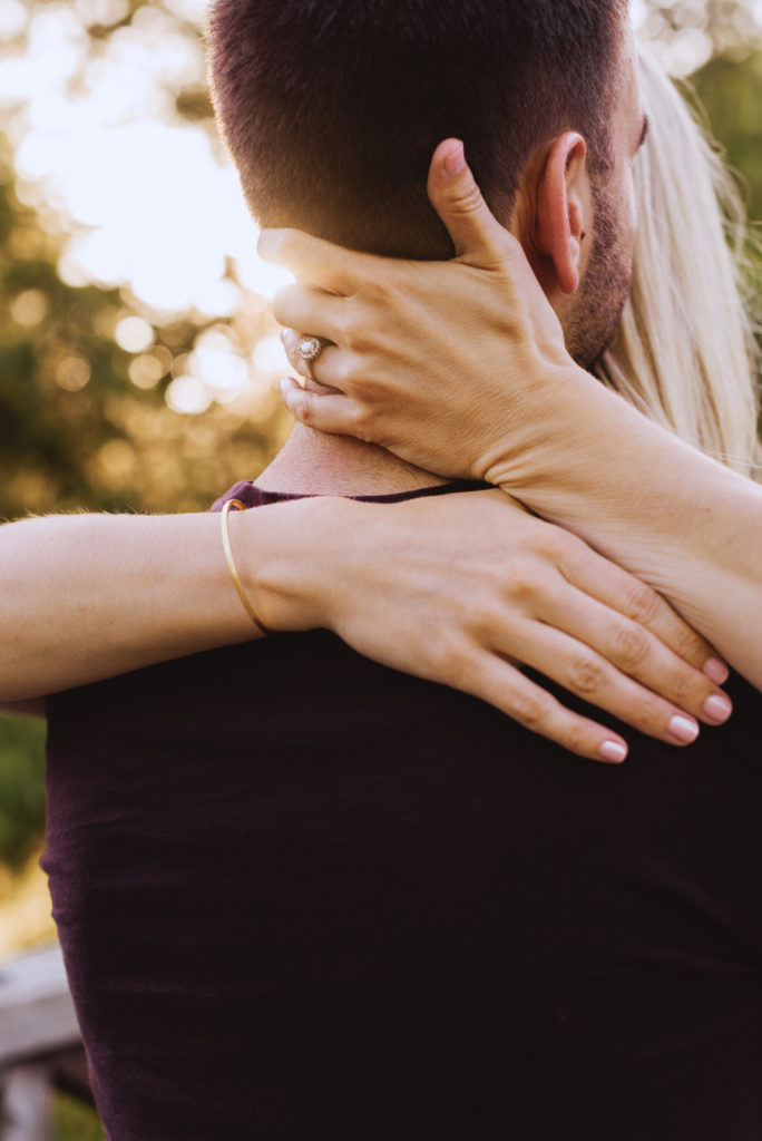 girl with her arms around her fiancee with diamond ring showing