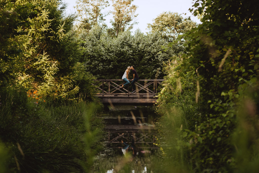 engaged couple sitting on a wooden bridge
