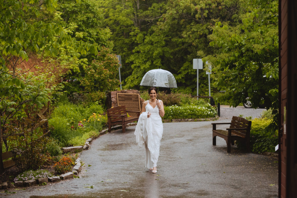 bride walking to first look holding clear umbrella in the rain
