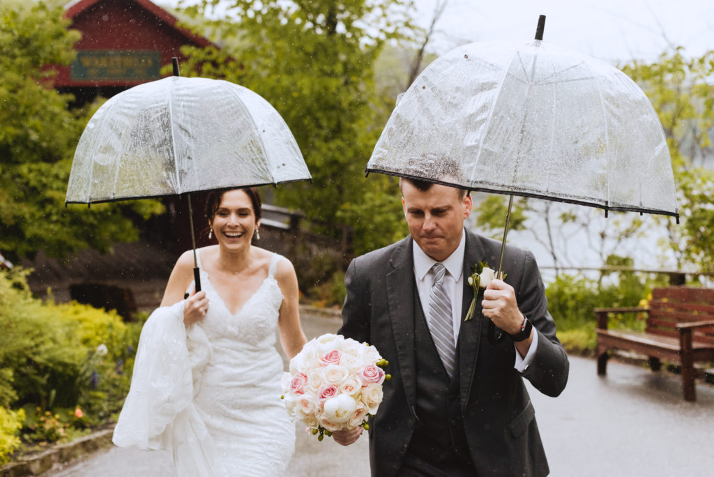 bride and groom walking with clear umbrellas in the rain