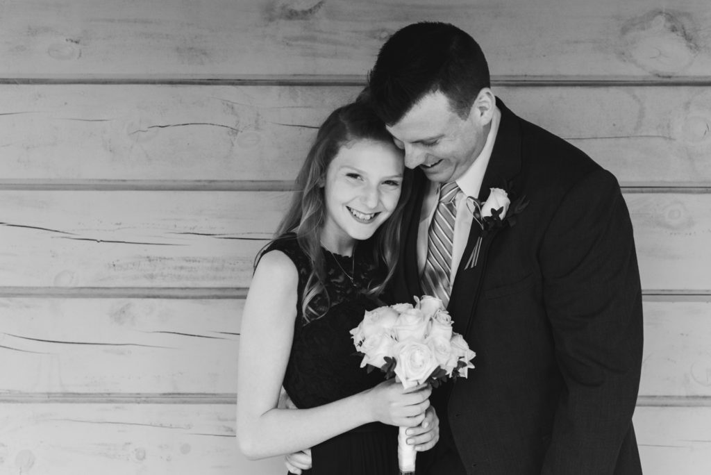 groom and his daughter laughing in black and white