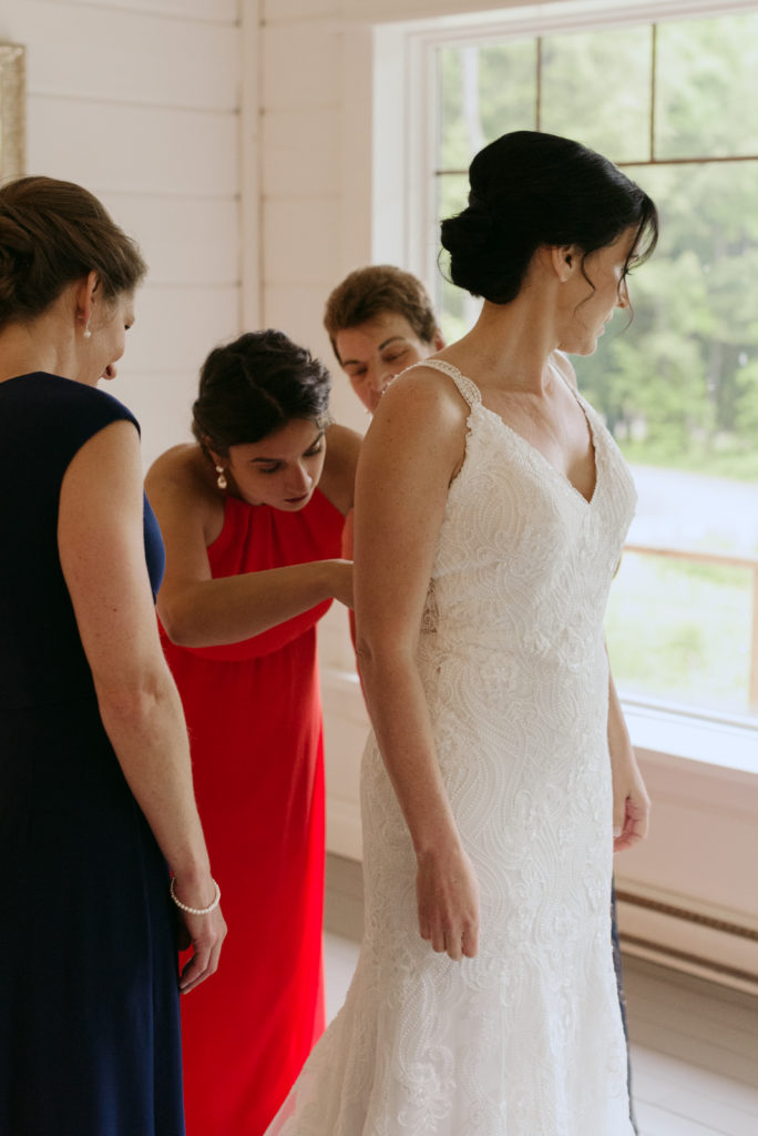 bride getting her dress on with the help of her friends