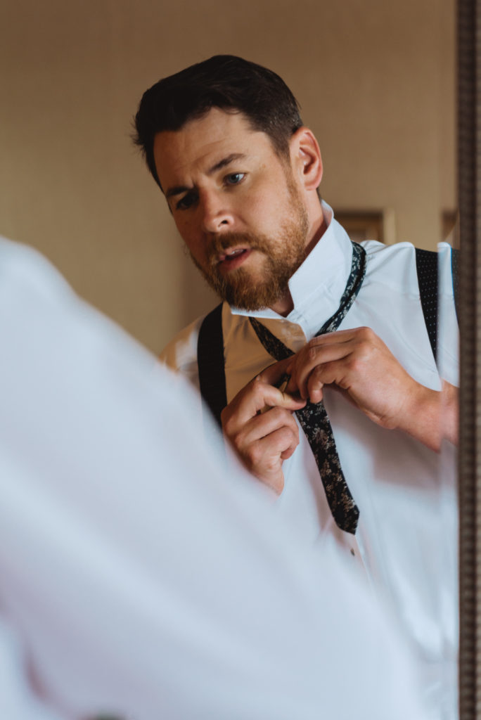 groom adjusting his tie in the mirror