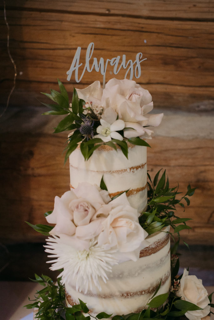 wedding cake with cake topper that says "always"