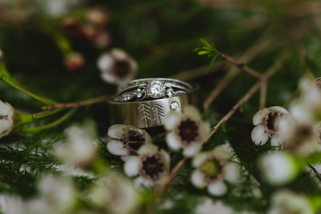 wedding rings in greenery with flowers
