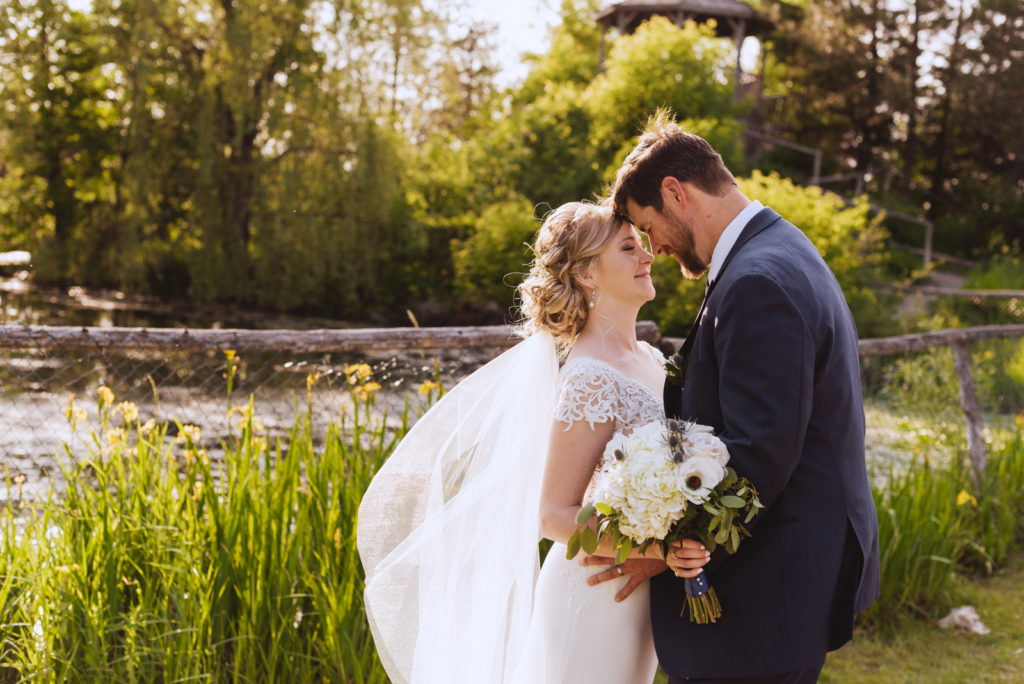 bride and groom cuddling by pond at Saunders Farm