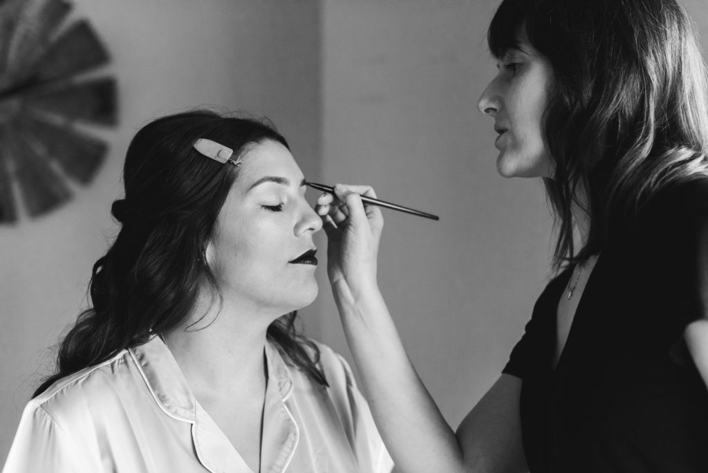 makeup artist putting on bridesmaid's makeup