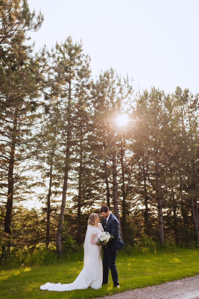 bride and groom with tall trees and sunshine
