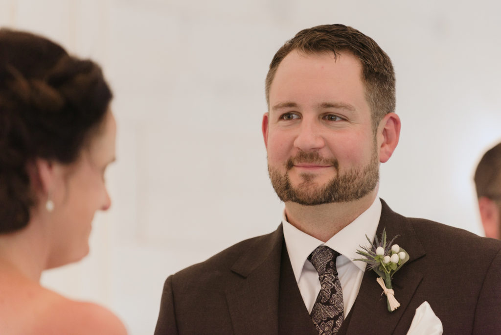groom smiling at bride during wedding ceremony