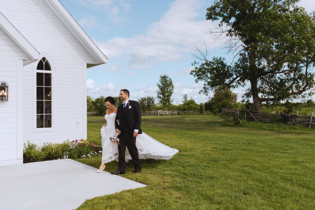 bride and groom walking by wedding chapel at Stonefields