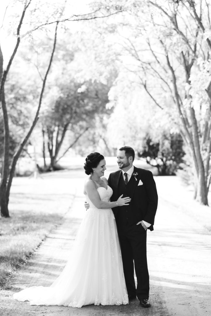 bride and groom on dirt road surrounded by trees