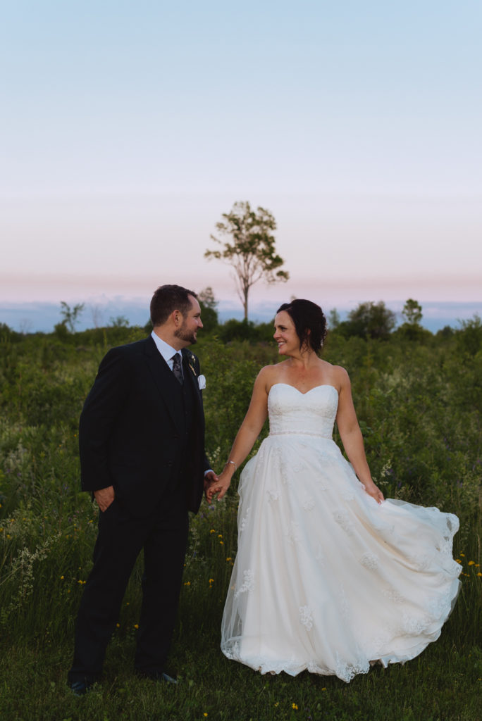 bride and groom in field at sunset