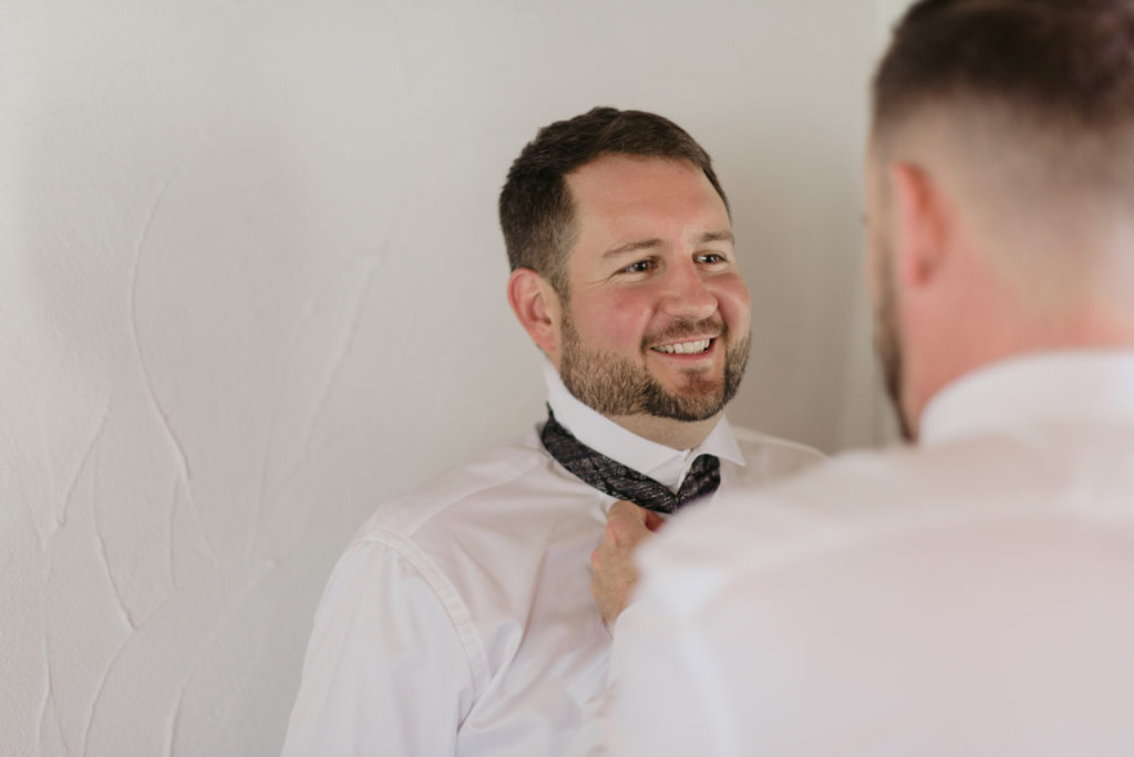 groomsman helping the groom with his tie