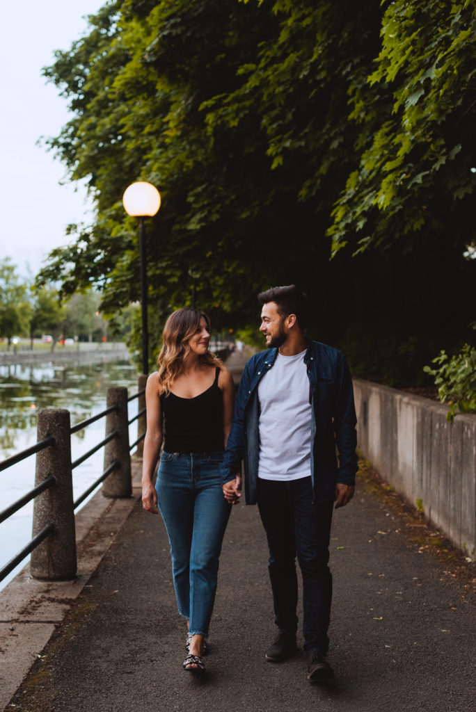 engaged couple walking along the canal holding hands