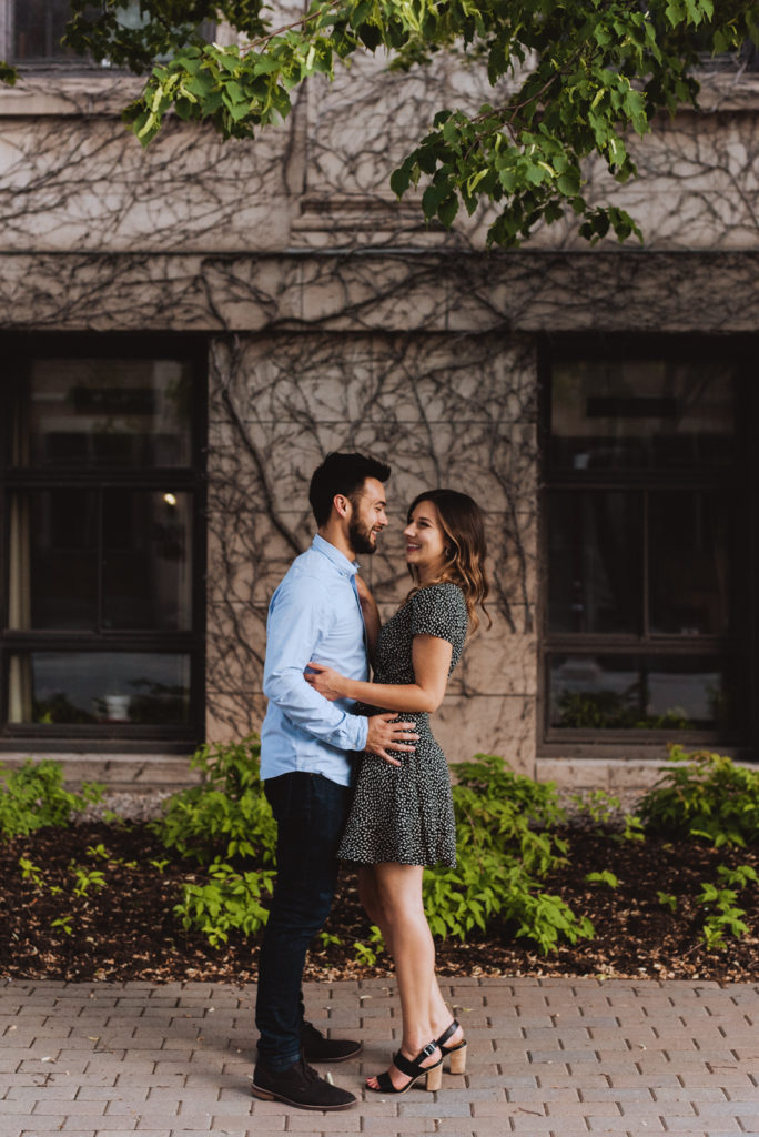 engaged couple laughing in front of old building with vines